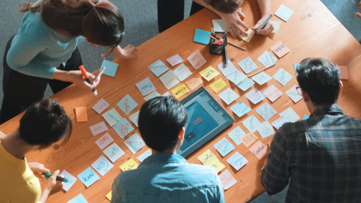 Top view of manager writing idea on sticky notes and explain idea. Symposium.